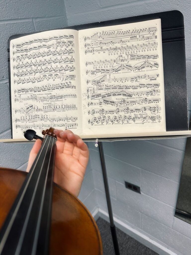 Close-up view of a violinist practicing with sheet music in a practice room, representing effective practice habits